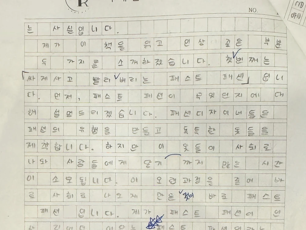 학원 전용 원고지에 또박또박 써 내려간 학생의 글과 선생님의 파란 펜 첨삭